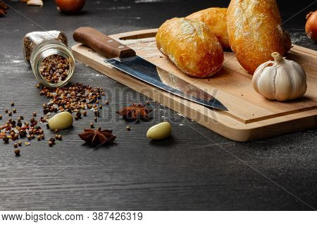 Fresh Wheat White Bread On A Cutting Board With Seasonings Sprinkled With Flour On A Black Wooden Ta