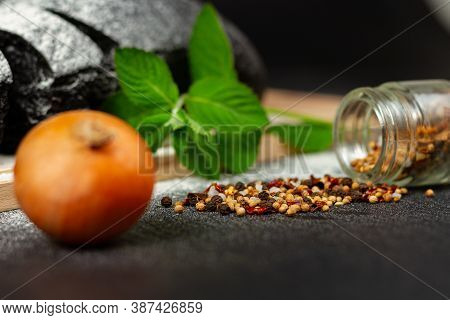 Fresh Black Rye Bread On A Cutting Board With Seasonings Sprinkled With Flour On A Black Wooden Tabl