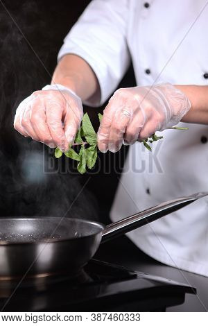 The Chef Adds Mint Leaves To The Pan. Preparation Of Dishes. Unrecognizable Vertical Photo. Flaming 