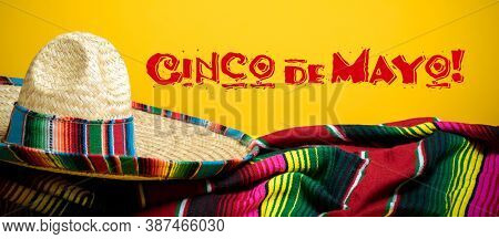 Mexican Serape blanket and sombrero on yellow background with Cinco de Mayo. 