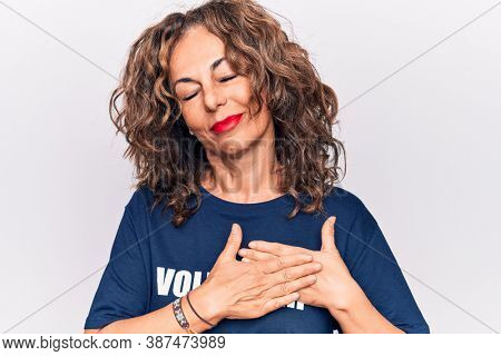 Middle age woman asking for social care wearing volunteer t-shirt over white background smiling with hands on chest, eyes closed with grateful gesture on face. Health concept.