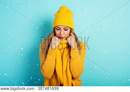 Woman Keeps Warm With Scarf And Hat In Winter. Cyan Background