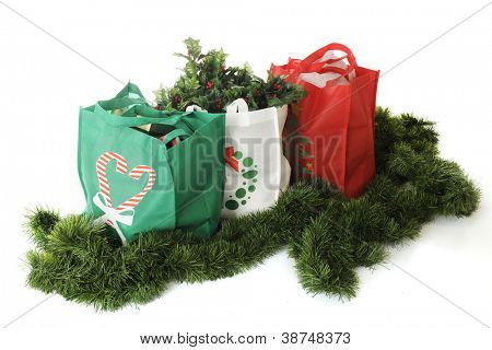 Vue aérienne de trois sacs à provisions réutilisables rempli de goodies Noël et entouré de verdure 