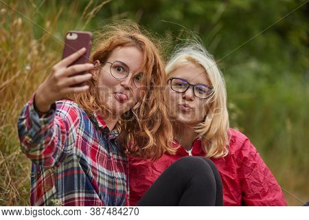 Girls taking selfies with a smartphone outoors in natural environment on a hikin trip