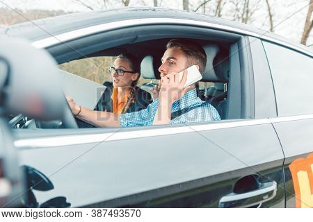 Driving instructor being rather mad at student using his telephone while driving