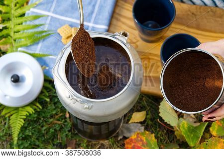 Young Beautiful Girl In A Yellow Sweater Makes Coffee In The Forest On A Gas Burner. Making Coffee O