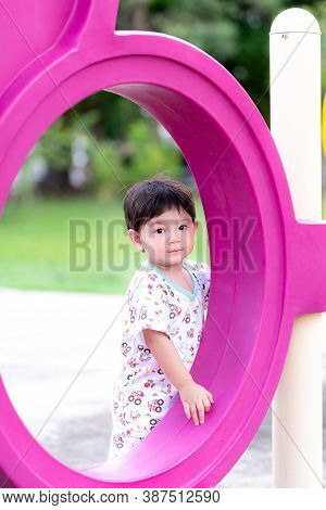 The Son Or Child Boy Stands Secretly Behind The Player On The Playground Near The House. An Asian Bo