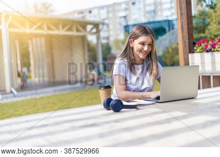 Woman With Headphones With Laptop Outside In Park