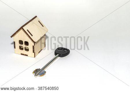 Small Toy House With Key Lying Next To It. The Concept Of Buying Your Own Home. The Protection Of Yo