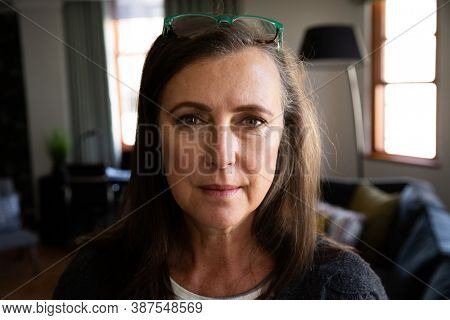 Portrait of  Caucasian woman enjoying time at home, social distancing and self isolation in quarantine lockdown, looking at camera in living room