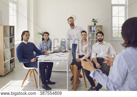 Group Of Colleagues Listening To Woman Partners Presentation Of New Project Or Startup In Office