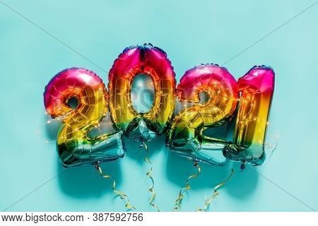 Rainbow colored Foil balloons in the form of numbers 2021 on blue background