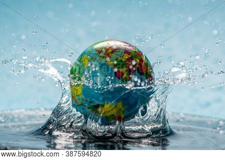 Planet Earth In The Form Of A Globe In Clear Water With Splashes. Concept Of Eco Friendly Behavior, 