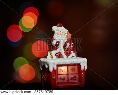 Santa Claus Statuette Doing An Exercise Waiting For Christmas. Colored Bokeh
