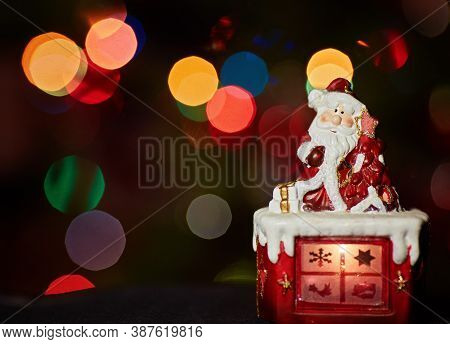 Santa Claus Statuette Doing An Exercise Waiting For Christmas. Colored Bokeh