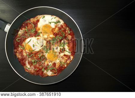 Shakshuka - Poached Eggs In Tomato Sauce, Onion, Pepper And In Iron Pan On Dark Wooden Table With Co