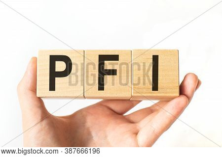 Hand Holds Wooden Cubes With Letters Pfi. Business Concept Image.