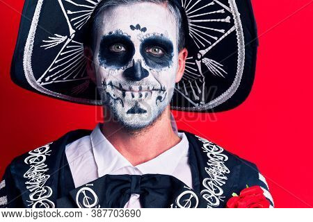 Young man wearing mexican day of the dead costume over red background looking positive and happy standing and smiling with a confident smile showing teeth 