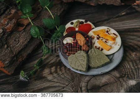 Hand Made Chocolates With Dried Fruits On A Small Plate On A Wooden Table.