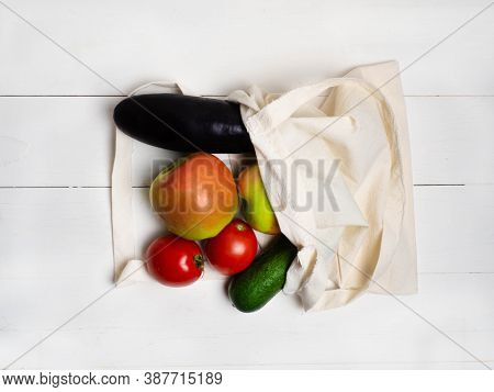 Various Vegetables And Fruits In An Eco-friendly Cloth Bag On A White Wooden Background, Top View. T