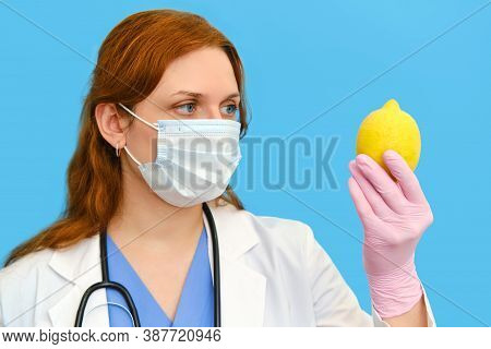 Woman Doctor Holding A Yellow Lemon On A Blue Background, Close-up.