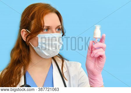 Woman Doctor Holding A Sanitizer On A Blue Background, Close-up.