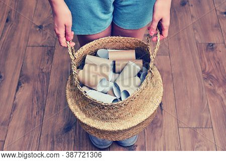 Female Hands Hold A Basket With Empty Rolls Of Finished Toilet Paper. Cardboard Recycling And Reuse 