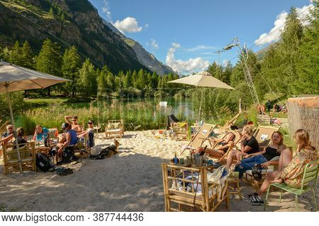 People Drinking In A Beach Bar Of The Lake At Tasch On The Swiss Alps