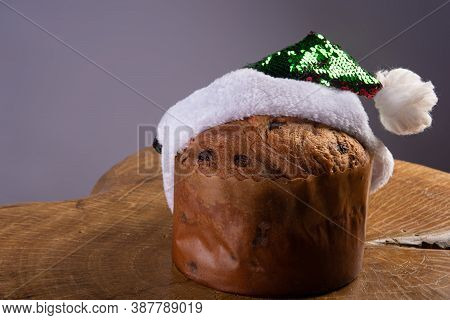 Panettone With Chocolate Chips And Santa Claus Hat On Rustic Wood With Gray Background, Selective Fo