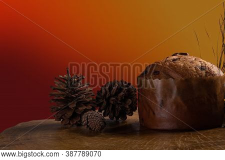 Panettone With Chocolate Chips On Rustic Wood With Pine Cones And Branches With Gradient Background
