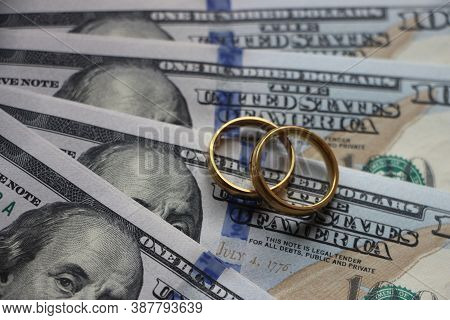 Wedding Rings On The Background Of 100 Dollars Bills. Marriage Conctract Or Prenuptial Agreement Con