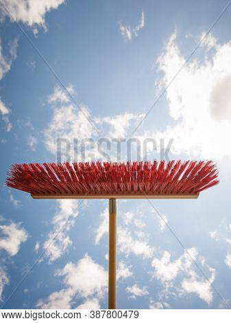 Broom Red Sweeping Brush Against Blue And White Cloudy Sky. Household Obejcts Concept.