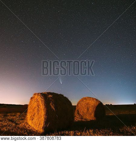 Meteor And Comet Neowise C2020 F3 In Night Starry Sky Above Haystacks In Summer Agricultural Field. 