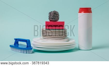 Dish Brushes, Cleaning Powder And A Set Of White Dishes On A Blue Background. The Concept Of Cleanin