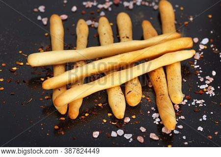 Pile Of Fresh Italian Grissini On Black Background With Sea Salt And . Close Up Breadsticks On Dark 