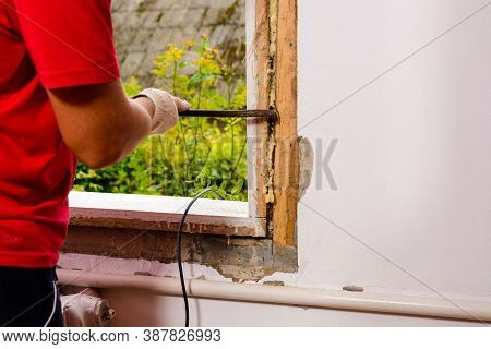 The Man With A Hand Saw Cuts The Mounting Wool Around The Window Frame, Installation Of An Old Woode