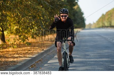 Smiling Man On A Road Bicycle On The Road. Cycling, Training, Feeling Happy During Physical Activity