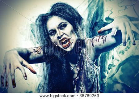 Bloodthirsty zombi standing at the night cemetery in the mist and moonlight.