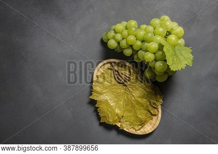 Grape Vine Leaf In Bowl With Fresh Grape Fruit On Rustic Background, Turkish Pickled Leaf Grows In T