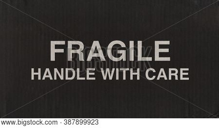 Fragile Handle With Care Warning Sign On Black Corrugated Cardboard Box