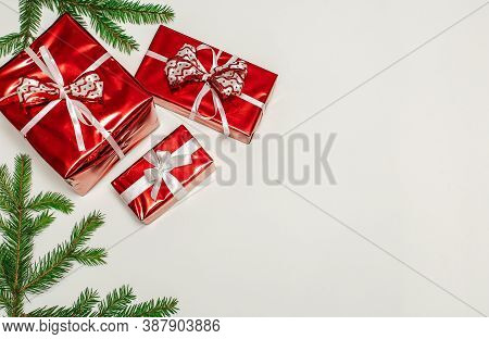 New Year's Composition, Fir Branches With Gifts In A Red Wrapper On A Vertical White Surface, Space 