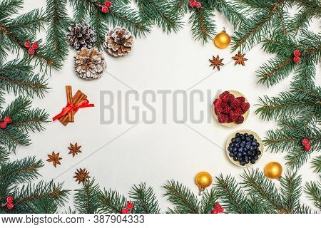 Christmas Layout. Berries, Cinnamon, Pine Cones On The Table,gold Ornaments On The Fir Branches. New