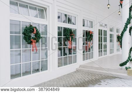 Christmas Decorations: Wreaths With Bows On The White French Windows Of A Private Home