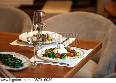 Restaurant Table Served With Spanish Buratta Tomato And Peppers Salads