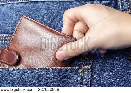 A Hand Pulls A Wallet Out Of The Back Pocket Of His Jeans.the Concept Of Pickpocketing Or Theft In T