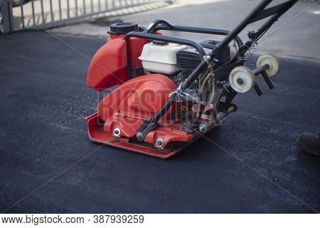 Asphalt Rammer. Laying The Road Surface. Creation Of Parking. The Worker Levels The Road Surface. Ho
