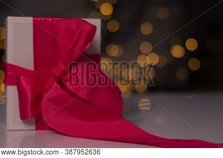 White Gift Box With Pink Ribbon Bow On Gold Bokeh Background