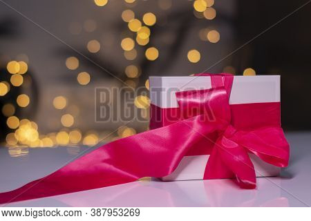 White Gift Box With Pink Ribbon Bow On Gold Bokeh Background
