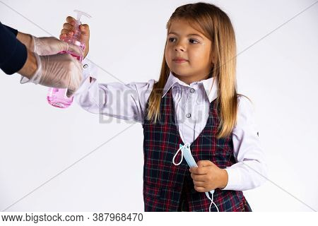 Confused Little Girl With Medicinal Mask In Her Hand And School Uniform Try To Take The Disinfectant