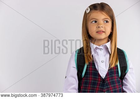School Girl Portrait On Gray Background. Shes Thoughtful.